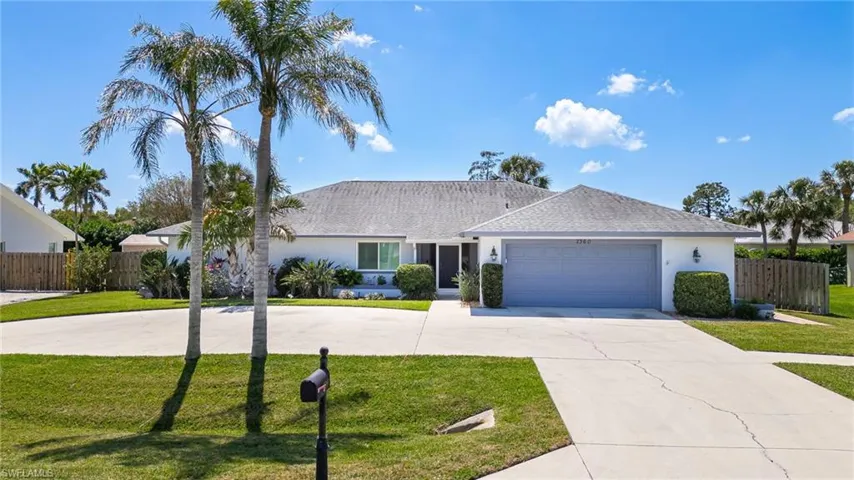 Ranch-style house featuring a garage, a front yard, driveway, and fence