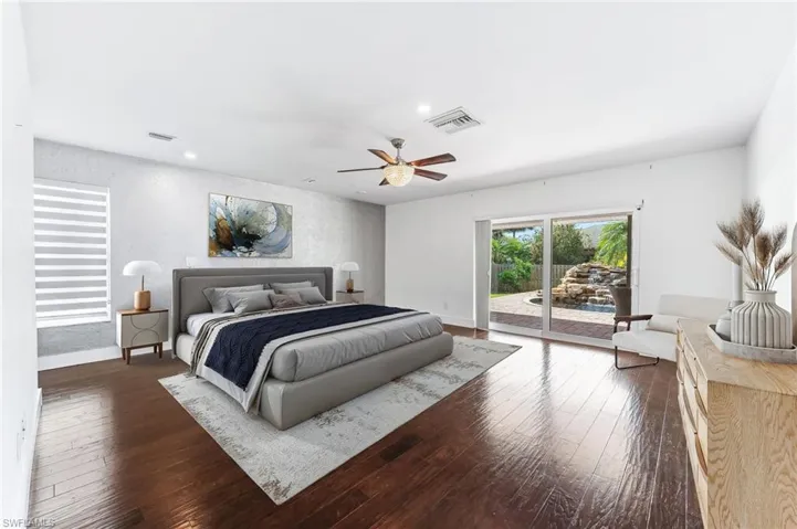 Bedroom featuring dark wood-style floors, visible vents, baseboards, and access to outside