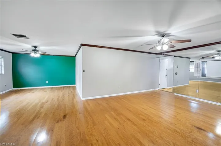 Unfurnished living room with ceiling fan, plenty of natural light, crown molding, and light wood-style floors