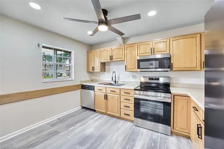 Kitchen with light brown cabinets, stainless steel appliances, light countertops, and recessed lighting