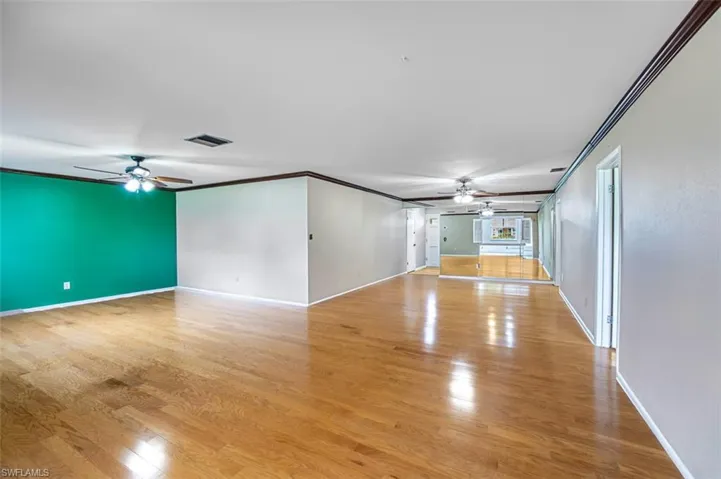 Unfurnished living room featuring a ceiling fan, light wood-type flooring, and crown molding