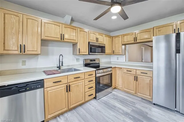 Kitchen featuring appliances with stainless steel finishes, light brown cabinetry, light countertops, and recessed lighting