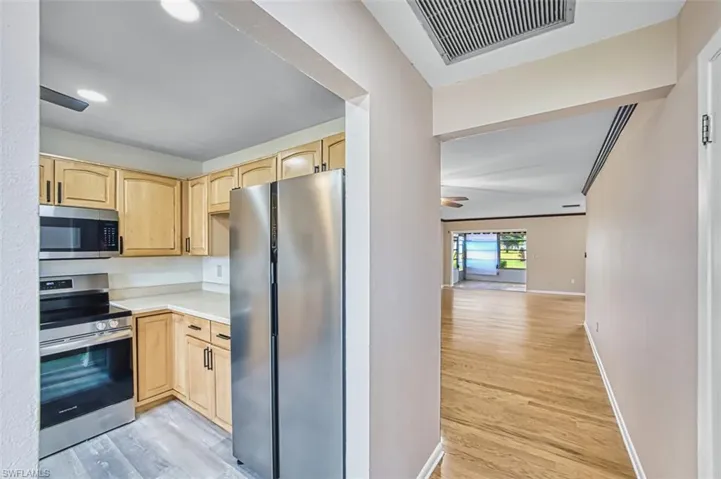 Kitchen featuring stainless steel appliances, light brown cabinetry, light countertops, light wood-style flooring, and recessed lighting