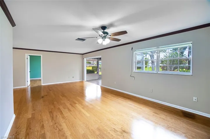 Spare room with crown molding, light wood-type flooring, and a ceiling fan