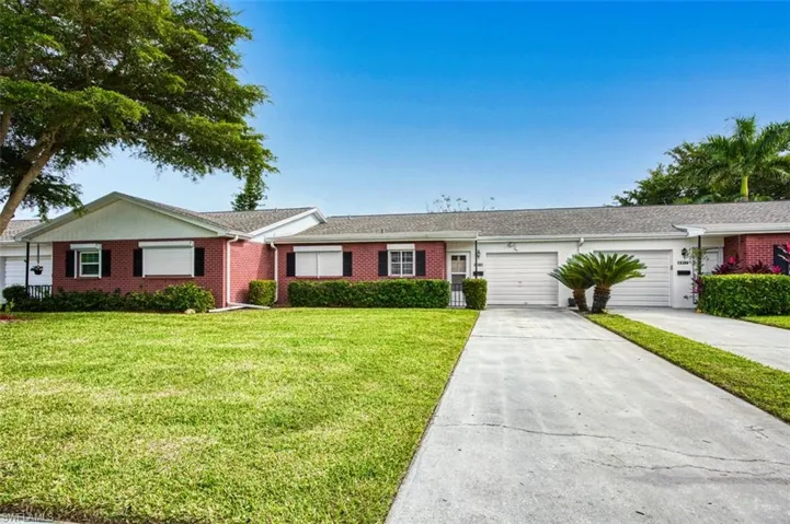 Ranch-style home featuring concrete driveway, brick siding, a front lawn, and a garage
