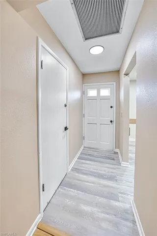 Doorway with a textured wall and wood finished floors