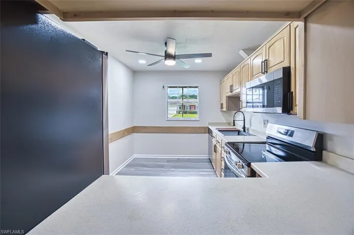 Kitchen featuring appliances with stainless steel finishes, light countertops, light brown cabinets, light wood-style flooring, and recessed lighting