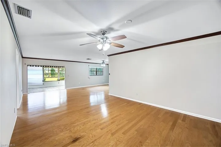 Spare room with crown molding, light wood-style floors, and ceiling fan