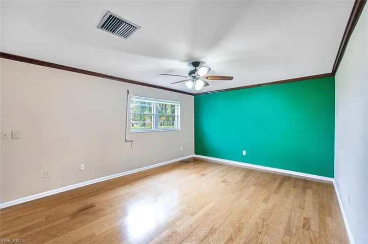 Unfurnished room with crown molding, light wood-style floors, and a ceiling fan