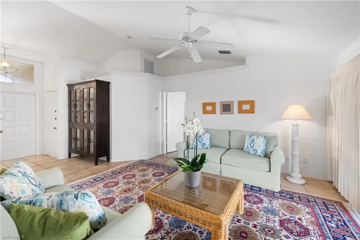 Living room featuring high vaulted ceiling, ceiling fan, and light tile patterned flooring