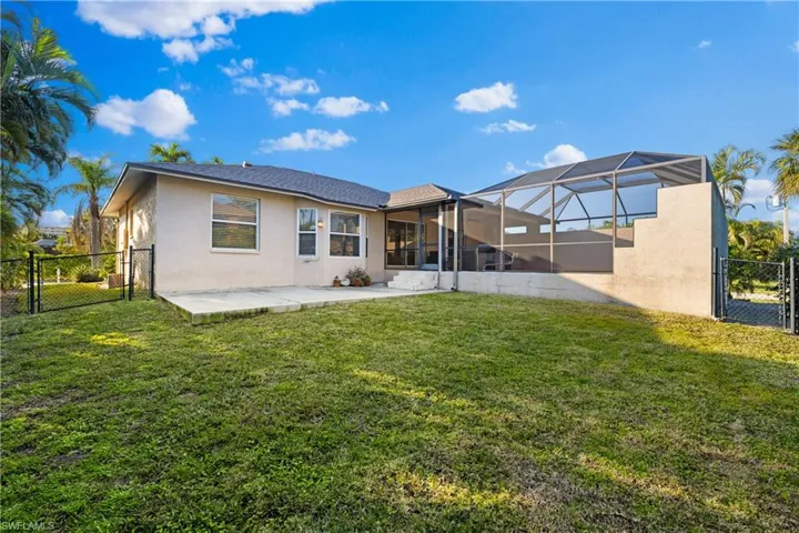 Rear view of property featuring a lawn, a patio area, and glass enclosure