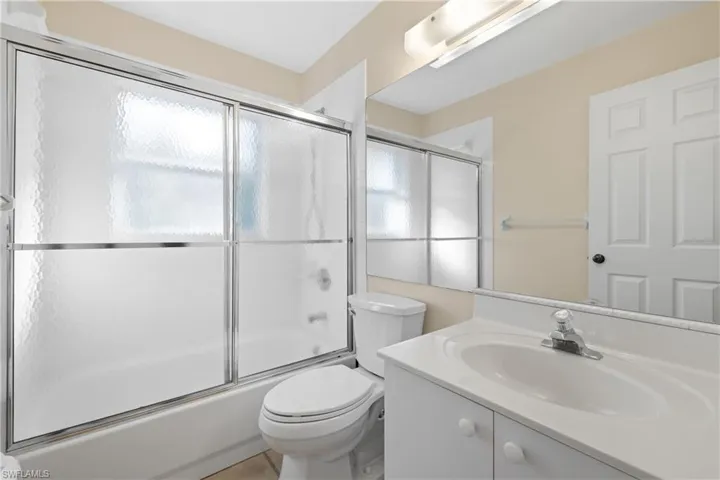 Full bathroom with combined bath / shower with glass door, vanity, plenty of natural light, and toilet
