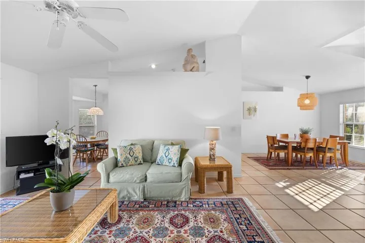 Tiled living room with ceiling fan and lofted ceiling
