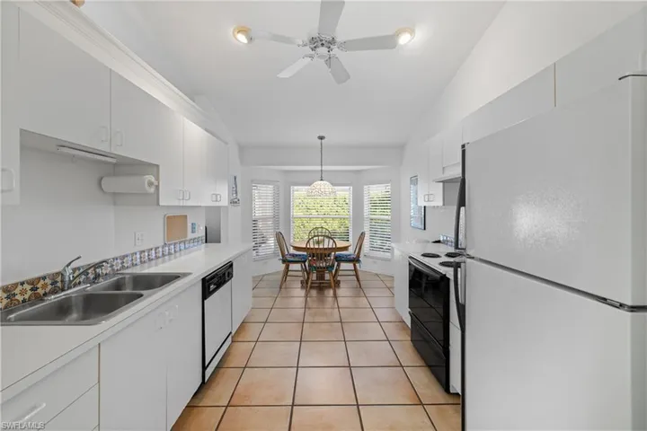 Kitchen with dishwashing machine, vaulted ceiling, white cabinets, and white fridge
