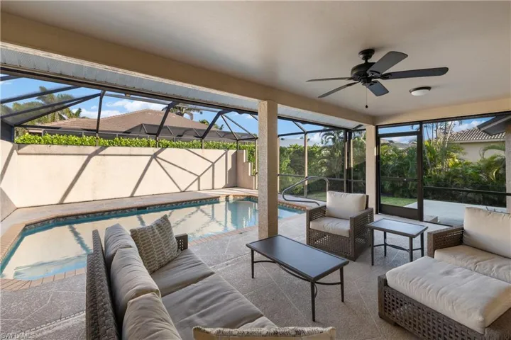 View of patio featuring ceiling fan, glass enclosure, and an outdoor living space