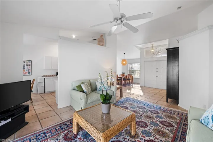 Living room with ceiling fan with notable chandelier and light tile patterned floors