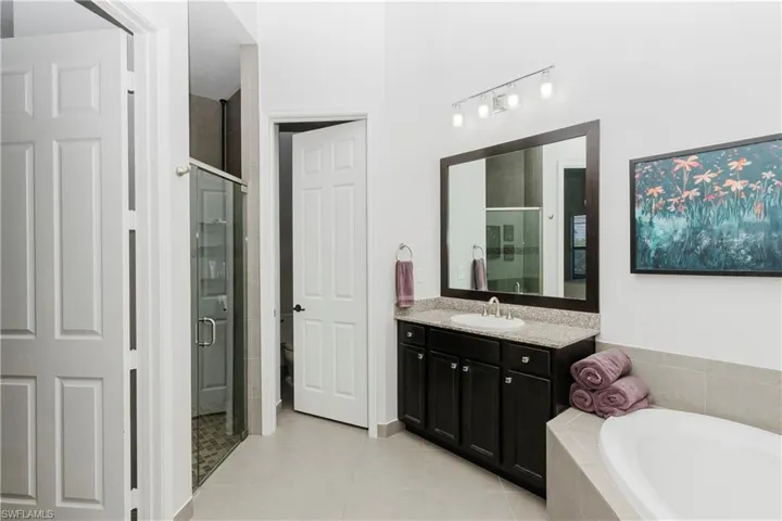 Full bath with vanity, a bath, a shower stall, and light tile patterned floors