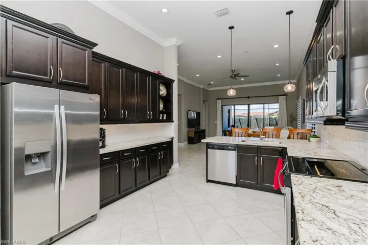Kitchen featuring stainless steel appliances, tasteful backsplash, ornamental molding, a ceiling fan, and light stone counters