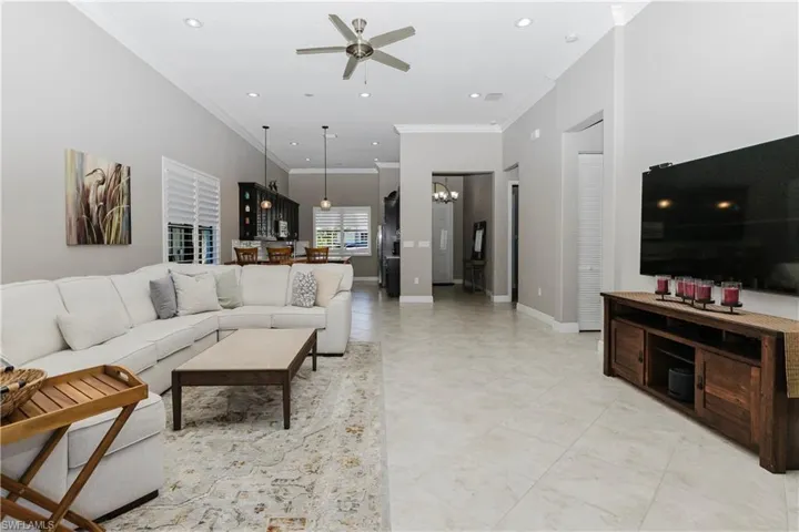 Living area featuring crown molding, a ceiling fan, recessed lighting, and a chandelier