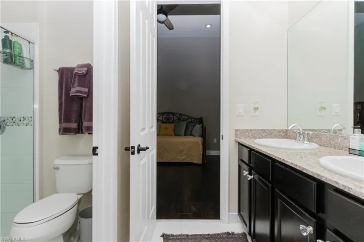 Full bathroom featuring ensuite bathroom, double vanity, a stall shower, and light wood finished floors