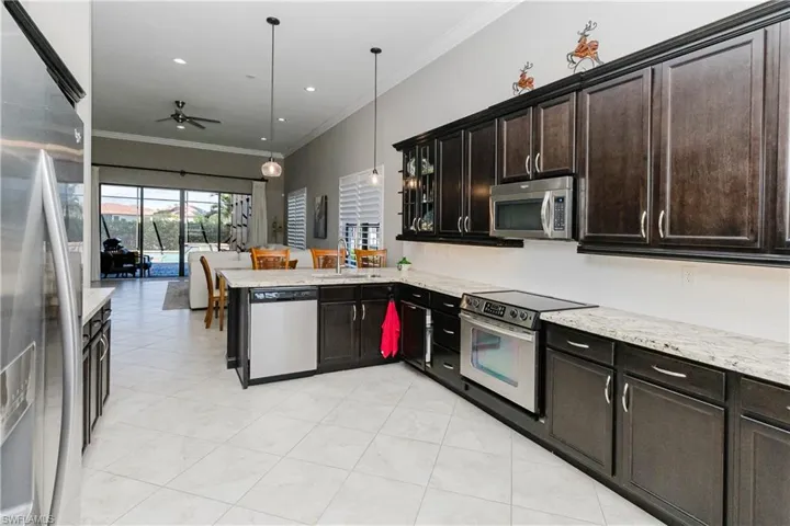 Kitchen with ornamental molding, stainless steel appliances, pendant lighting, tasteful backsplash, and light stone countertops