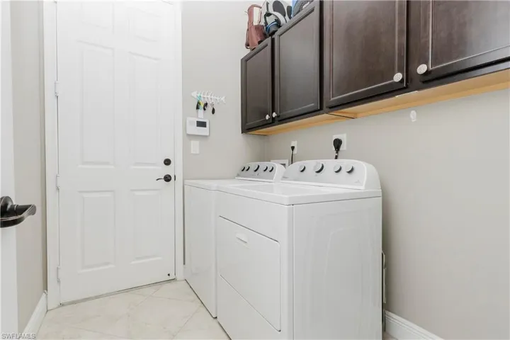 Washroom with washing machine and clothes dryer, cabinet space, and light tile patterned floors