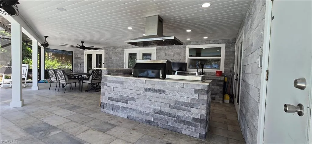 View of patio with area for grilling, outdoor dining area, ceiling fan, and french doors