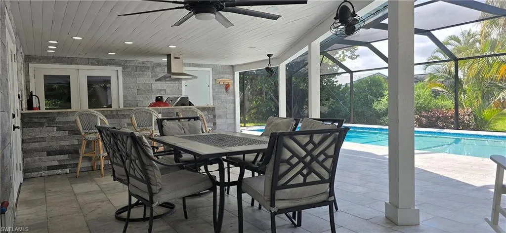 View of patio with a ceiling fan, an outdoor pool, french doors, and glass enclosure