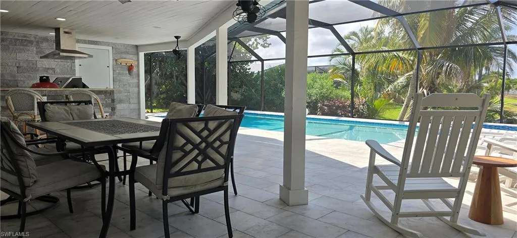 Swimming pool with exterior kitchen, a patio, outdoor dining space, and glass enclosure