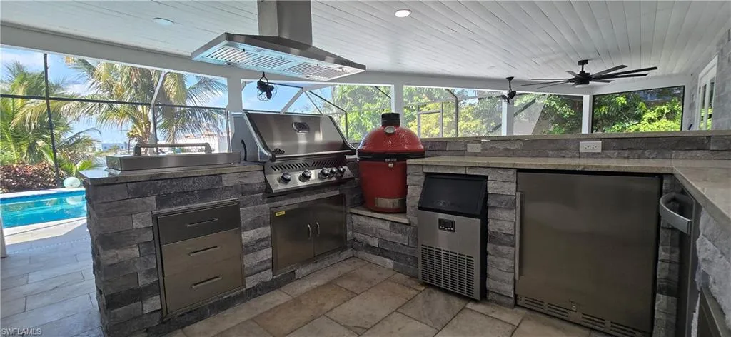 View of patio with exterior kitchen, grilling area, a lanai, and an outdoor pool