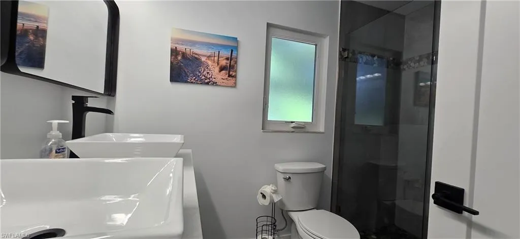Bathroom featuring a sink, a shower stall, and toilet