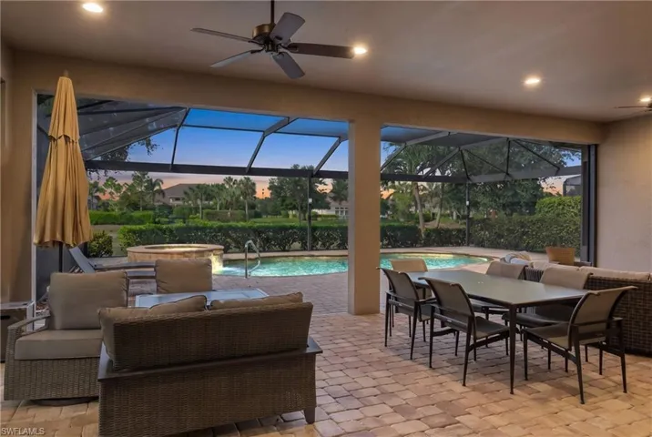 Screened outdoor living area featuring a built-in pool, integrated spa, and paver patio