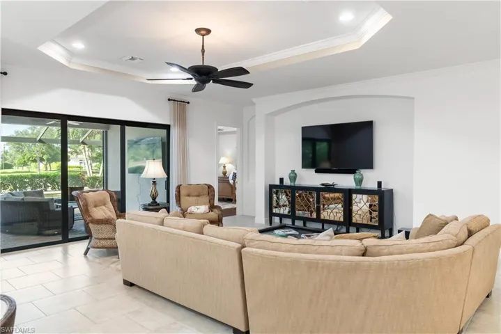 Tray ceiling with recessed lighting and a ceiling fan, large sliding glass doors, arched wall niche, and tile flooring