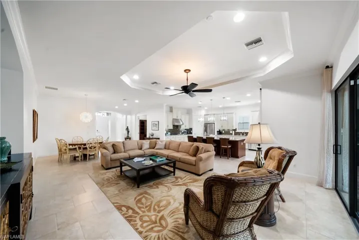 Tray ceiling with recessed lighting, large format tile flooring, sliding glass door, modern ceiling fan, and open-concept design