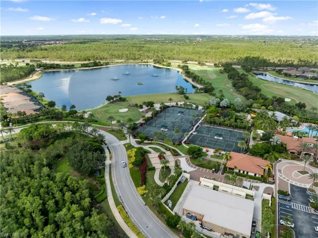 Expansive water feature with multiple fountains, adjacent golf course, multiple tennis courts, and surrounding residential structures