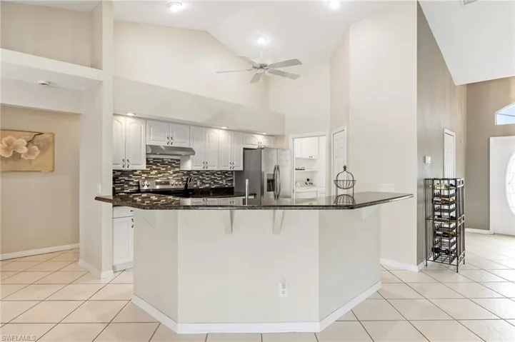 Open kitchen concept with granite countertops and volume ceilings