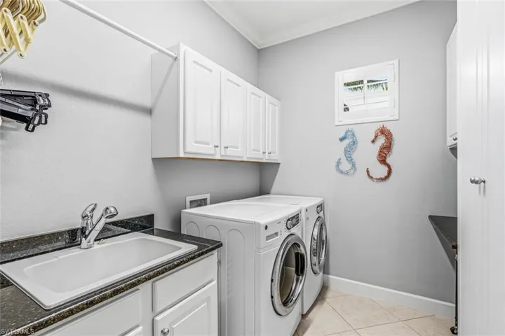 Laundry room with separate washer and dryer, light tile patterned flooring, cabinet space, and crown molding