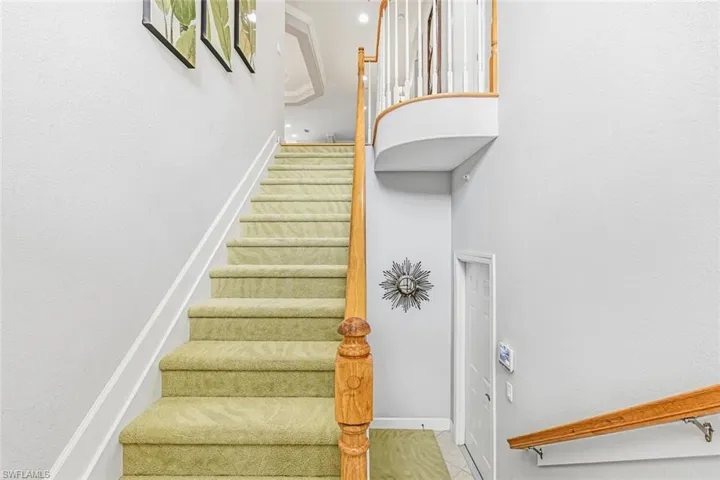 Stairs featuring baseboards and a towering ceiling