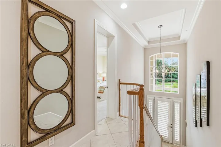Foyer with a chandelier, a raised ceiling, light tile patterned floors, and ornamental molding