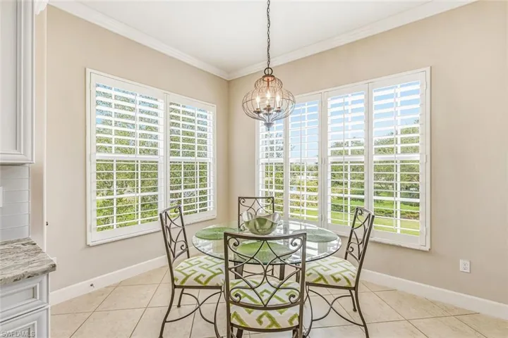 Dining area with light tile patterned floors, crown molding, and a chandelier