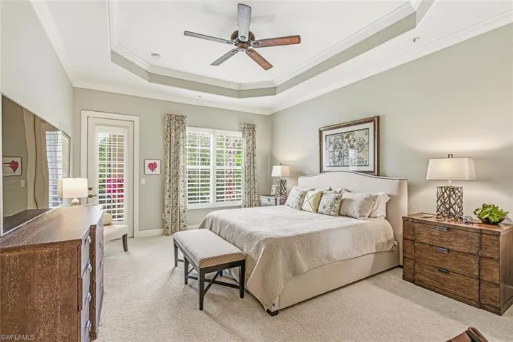 Bedroom featuring access to exterior, a raised ceiling, ornamental molding, carpet floors, and a ceiling fan