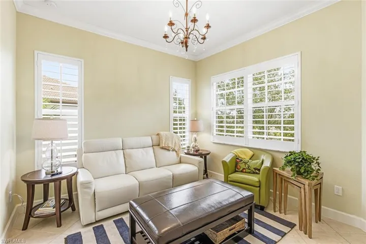 Living area featuring light tile patterned floors, crown molding, and a chandelier
