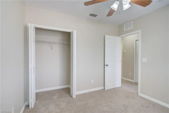 Unfurnished bedroom with ceiling fan, a closet, and light colored carpet