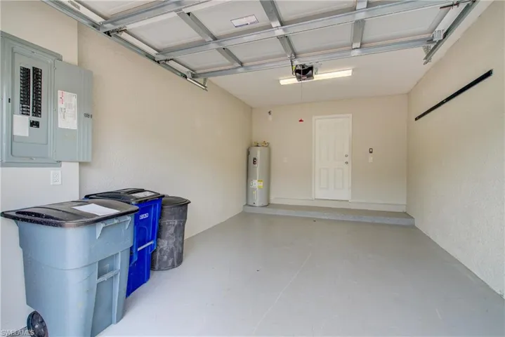 Garage with water heater, a garage door opener, and electric panel