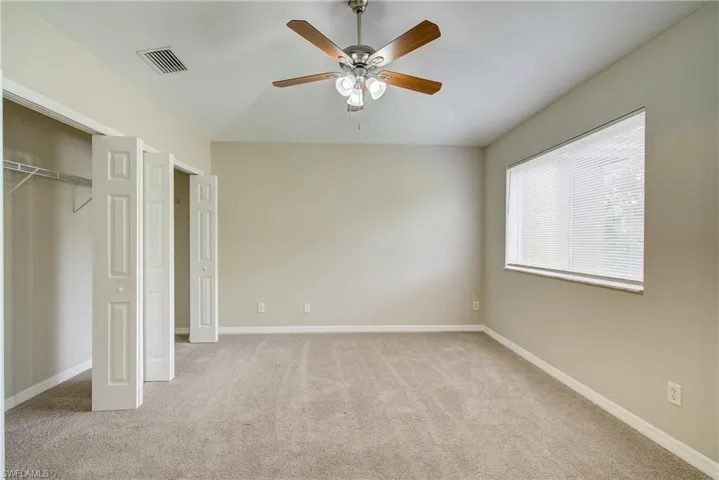 Unfurnished bedroom featuring light carpet, ceiling fan, and lofted ceiling
