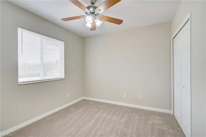 Unfurnished bedroom featuring a closet, light colored carpet, and ceiling fan