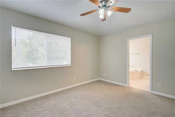 Unfurnished bedroom with ceiling fan, light colored carpet, a spacious closet, and connected bathroom
