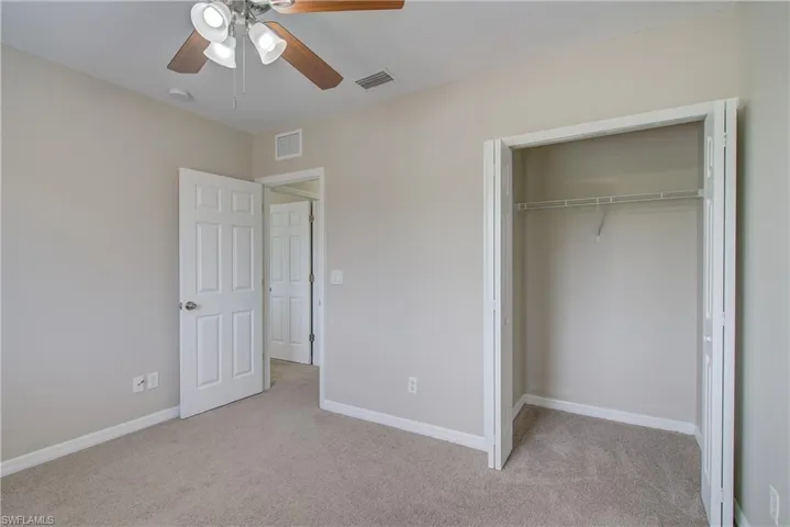 Unfurnished bedroom featuring ceiling fan, a closet, and light carpet