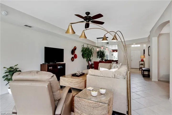 Living room featuring light tile patterned floors, ceiling fan, and arched walkways