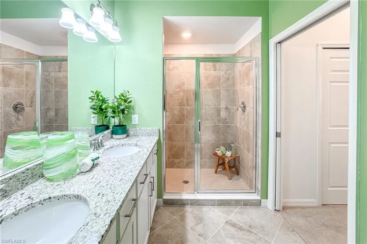 Full bathroom with double vanity, a shower stall, and tile patterned floors